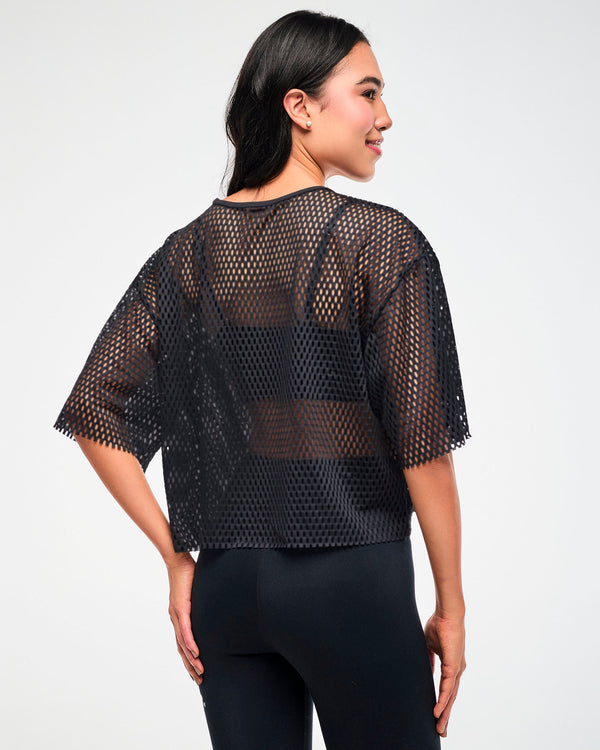 Back view of the black mesh cropped top, female model, paired with black leggings.