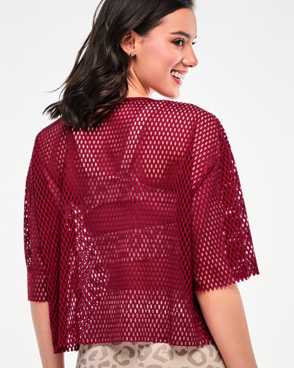 Shown from the back, a female model wears the dark red mesh crop top, showing its boxy, drop shoulder fit and raw-edge hems.