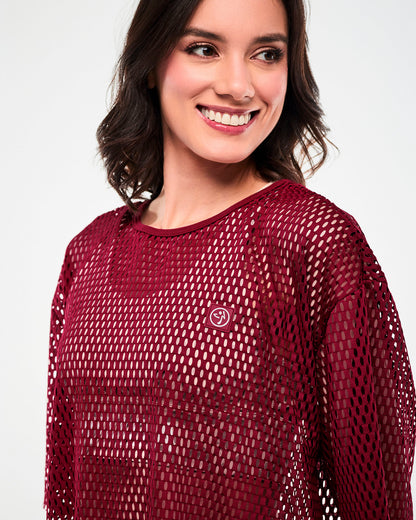 Close-up of the dark red mesh crop top, showing the bound crew neckline and a square dark red patch with a white Zumbito logo on the upper left chest.