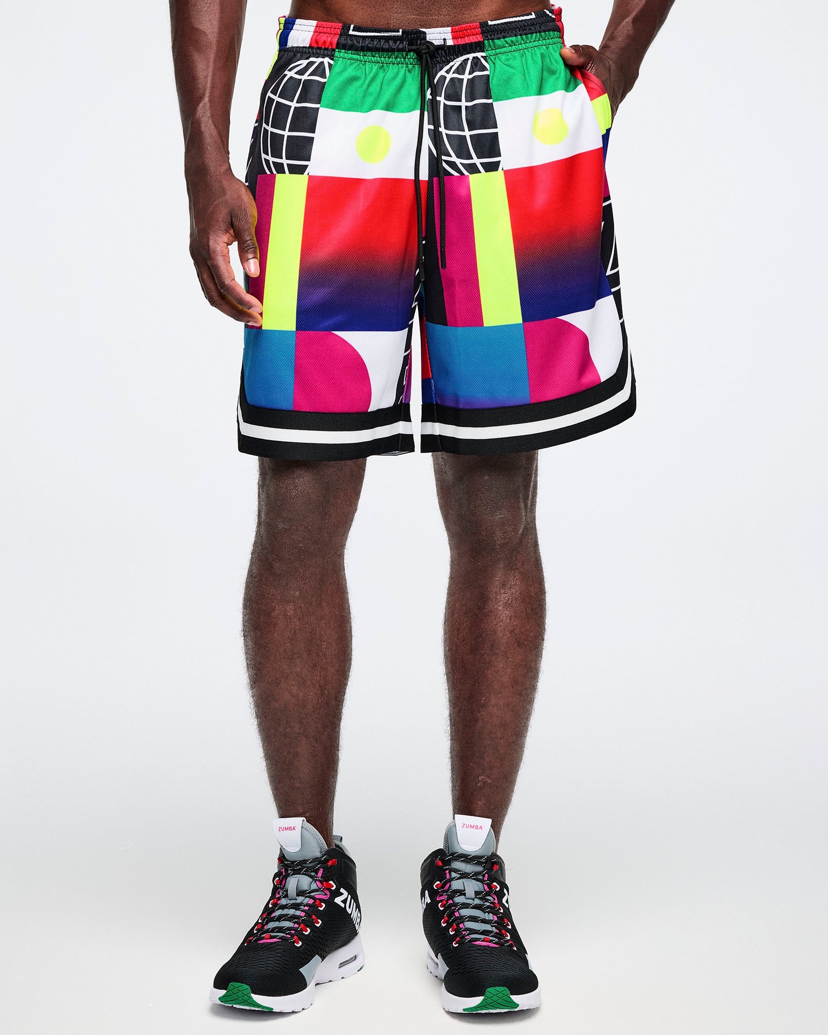 Male model in vibrant geometric basketball shorts with drawcord, black sneakers; clean white studio background.