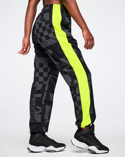 Right side view of a male model wearing black and gray patterned pants with neon yellow stripe down the leg on a white background.