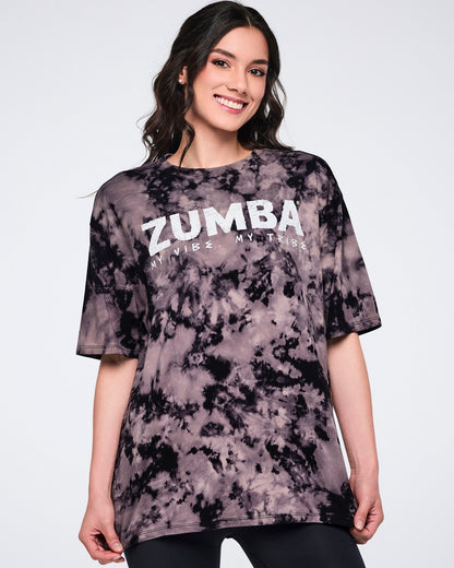 Oversized black and tan tie-dye Zumba T-shirt with a white “ZUMBA My Vibe. My Tribe.” graphic on the front. Female model wears the loose-fit crewneck tee with short sleeves and black leggings.