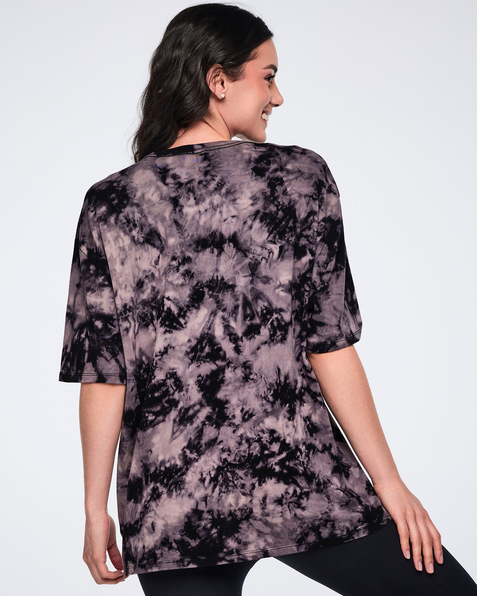 Oversized black and tan tie-dye Zumba T-shirt shown from the back. Female model wears the loose-fit crewneck tee with short sleeves and black leggings.