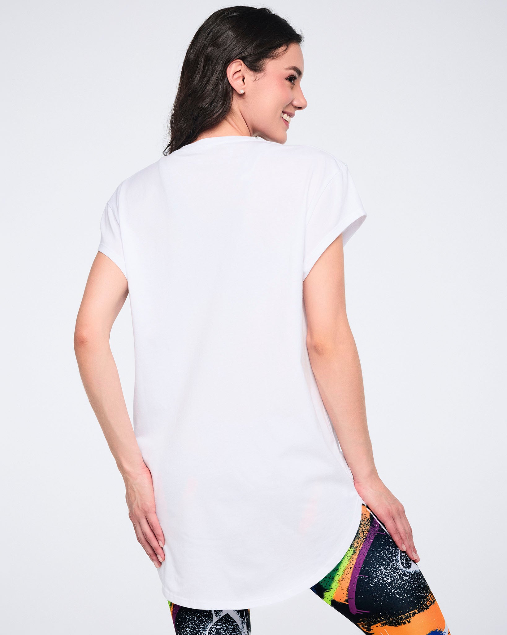 Back view of a female model wearing a white t-shirt with colorful leggings, on a white background.