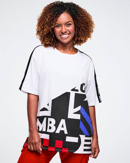 Female model wearing a white t-shirt with black, blue, and red design with red cargo pants on a plain background.