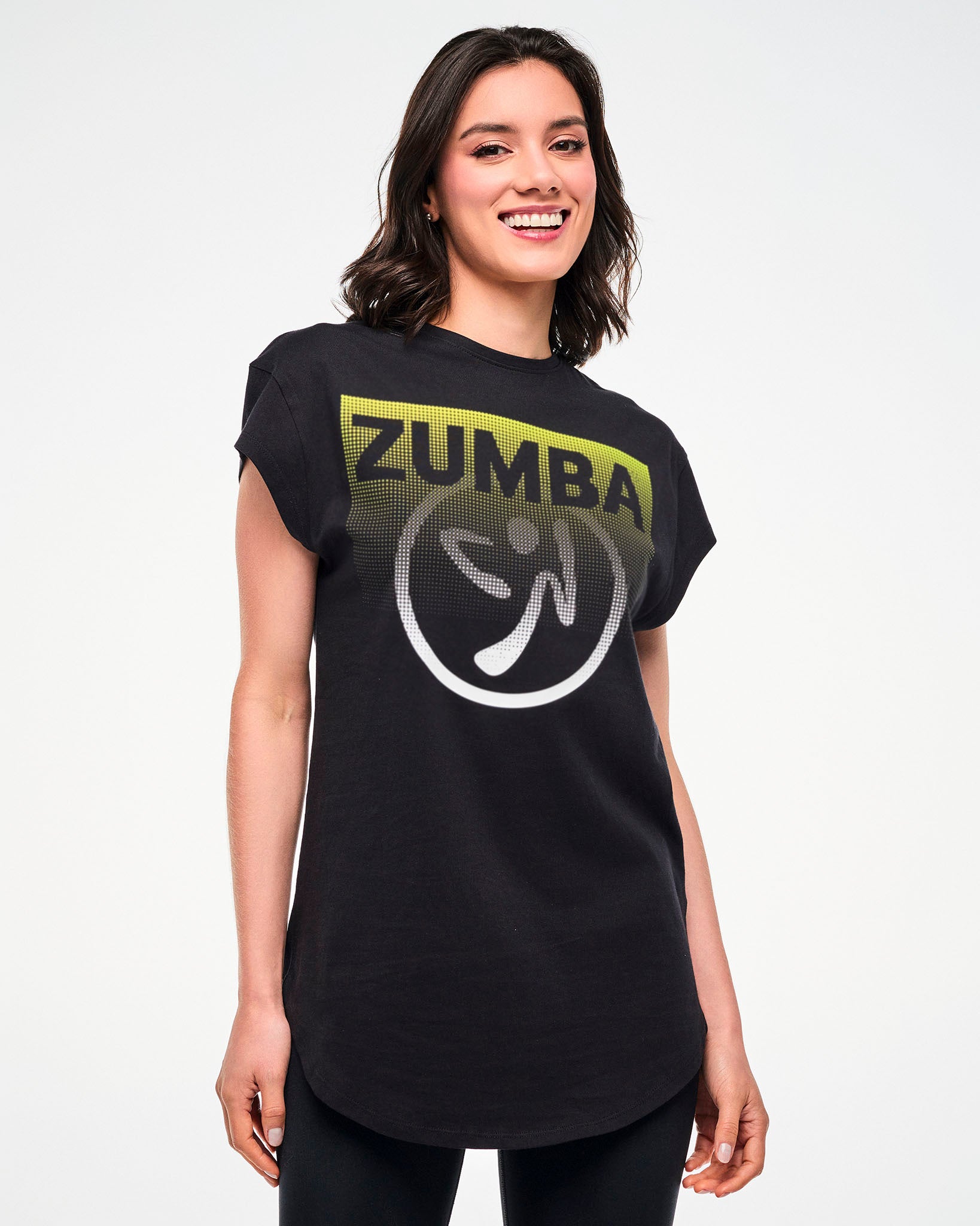 Female model wearing a black tee with a yellow-to-white gradient "ZUMBA" logo and Zumbito graphic.