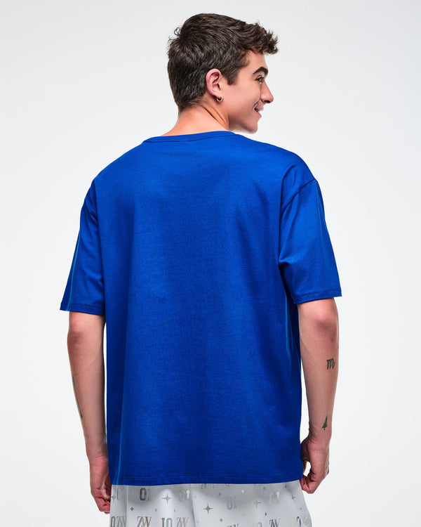 Back view of a male model wearing a blue Zumba t-shirt on a white background.