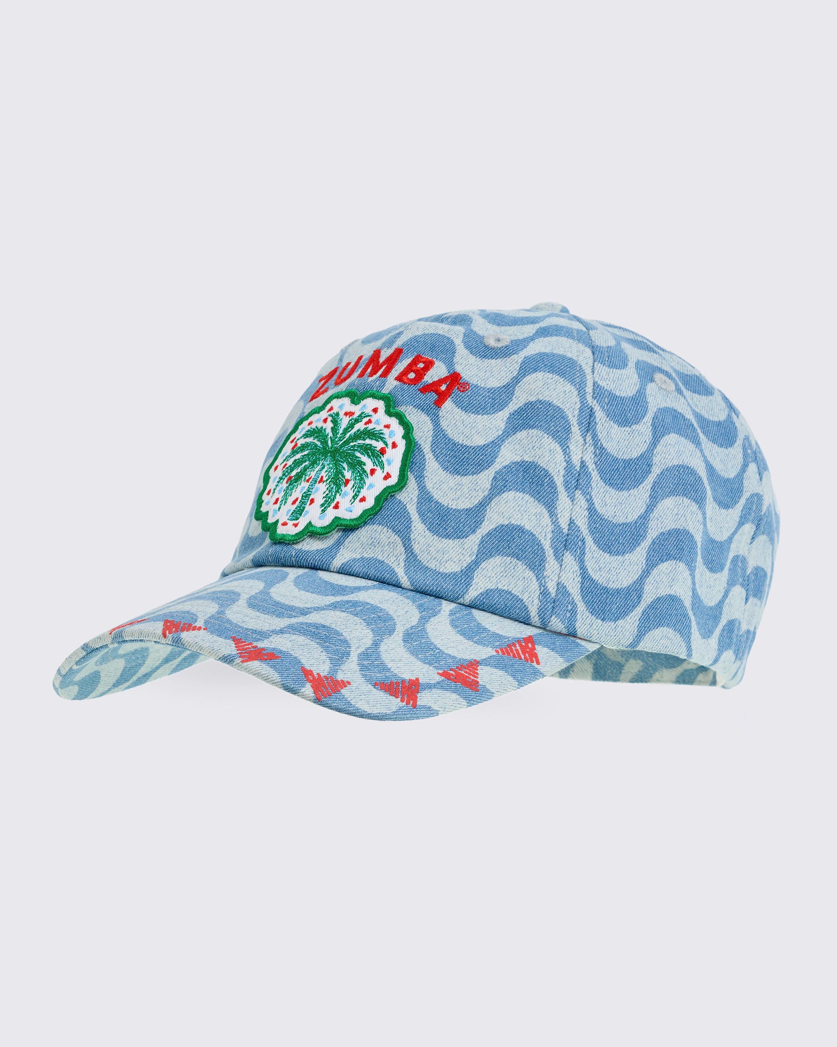 Light blue wavy-print baseball cap with embroidered “ZUMBA” text and palm-tree patch on the front, shown at an angle on a white background.