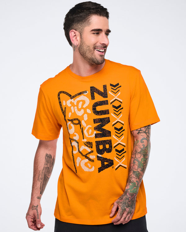 Male model wearing a bright orange short-sleeve Zumba T-shirt with a large black-and-white vertical graphic, abstract animal face artwork, and black bottoms.