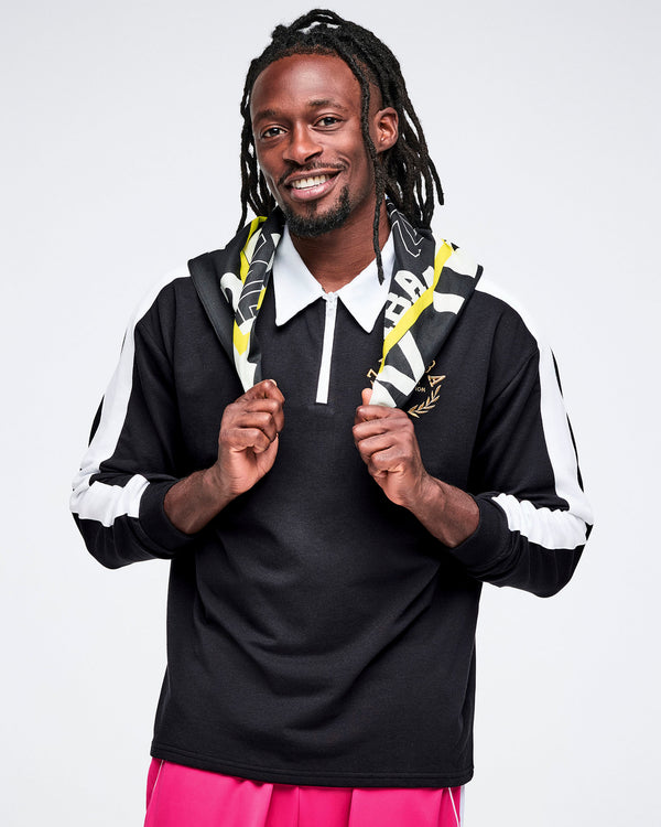Male model wearing a black polo with white stripes and a colorful bandana, standing against a white background.