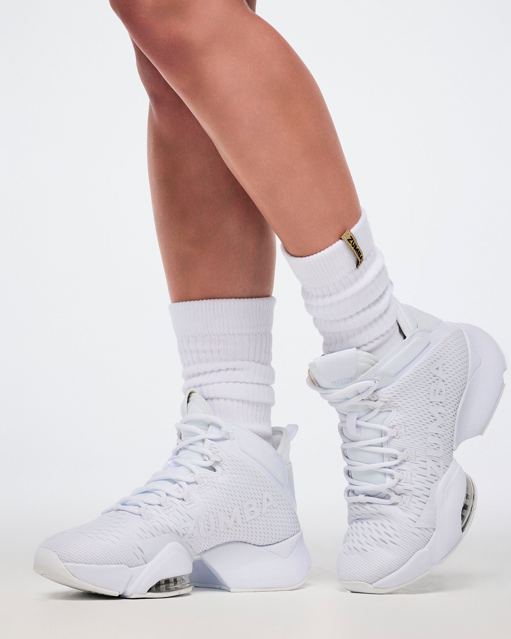 White high-top sneakers worn with white socks on a light background.