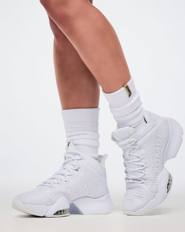 White high-top sneakers worn with white socks on a light background.