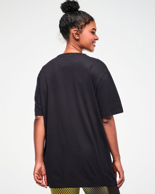 Shown from the back, female model wearing an oversized black T-shirt.