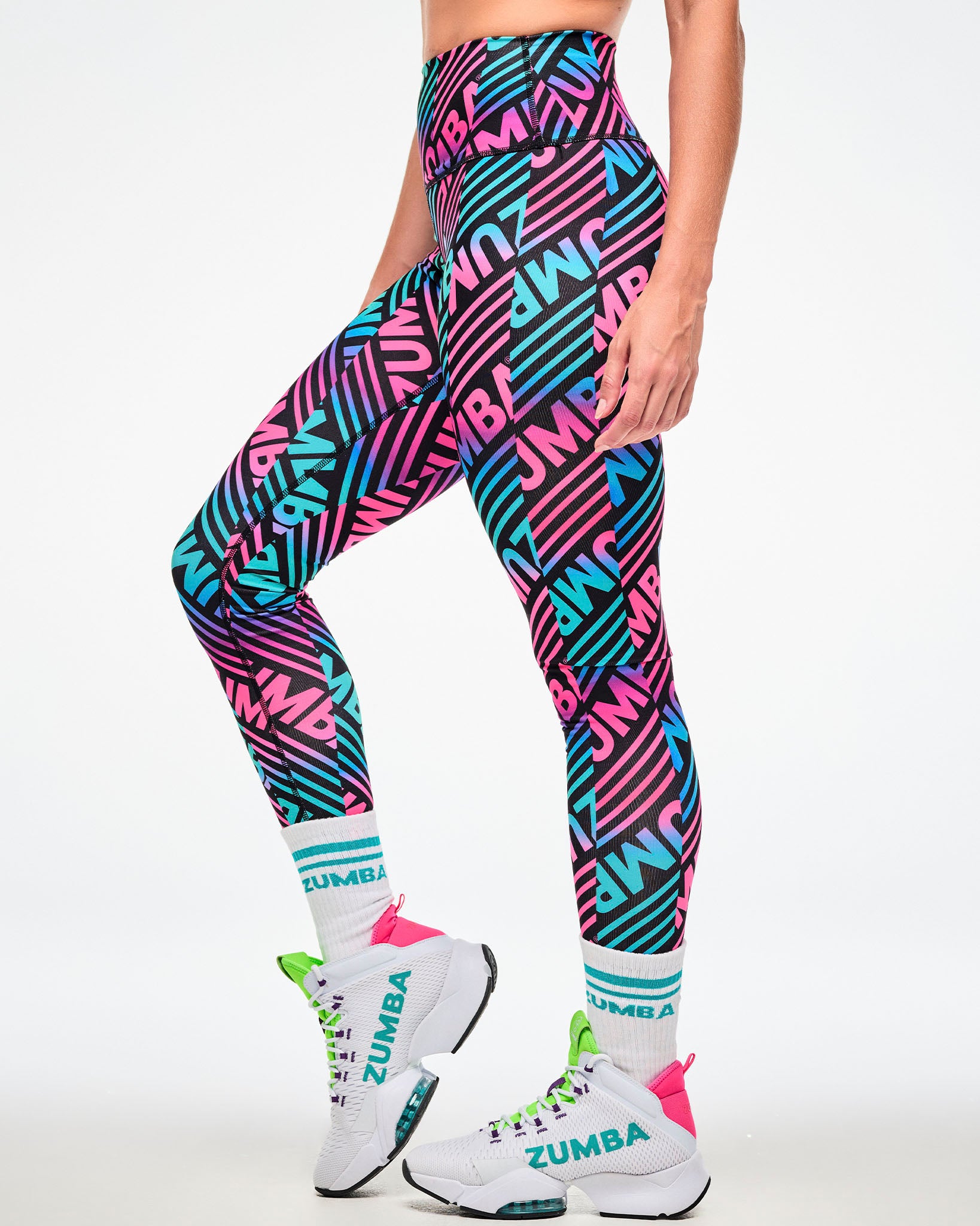 Female model wearing multicolor striped leggings with aqua-striped "ZUMBA" socks, shown from the side and white shoes.