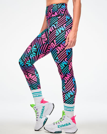 Female model wearing multicolor striped leggings with aqua-striped "ZUMBA" socks, shown from the side and white shoes.