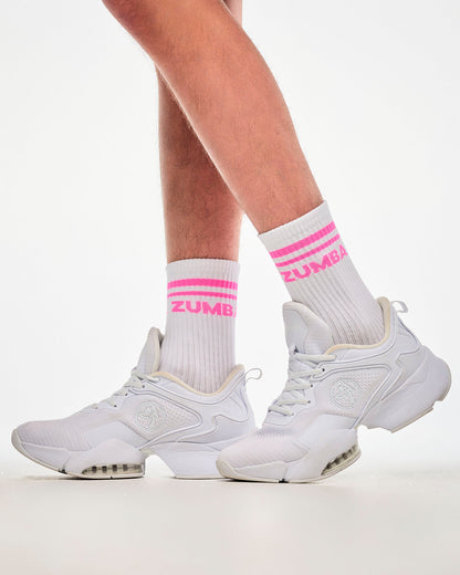 Close-up of white crew socks with pink stripes and "ZUMBA" text, paired with white shoes.
