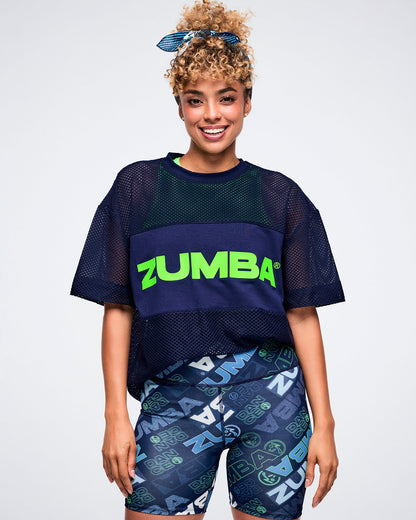 Female model in a Zumba outfit featuring a navy top, patterned shorts, and a blue bandana as a hair tie.