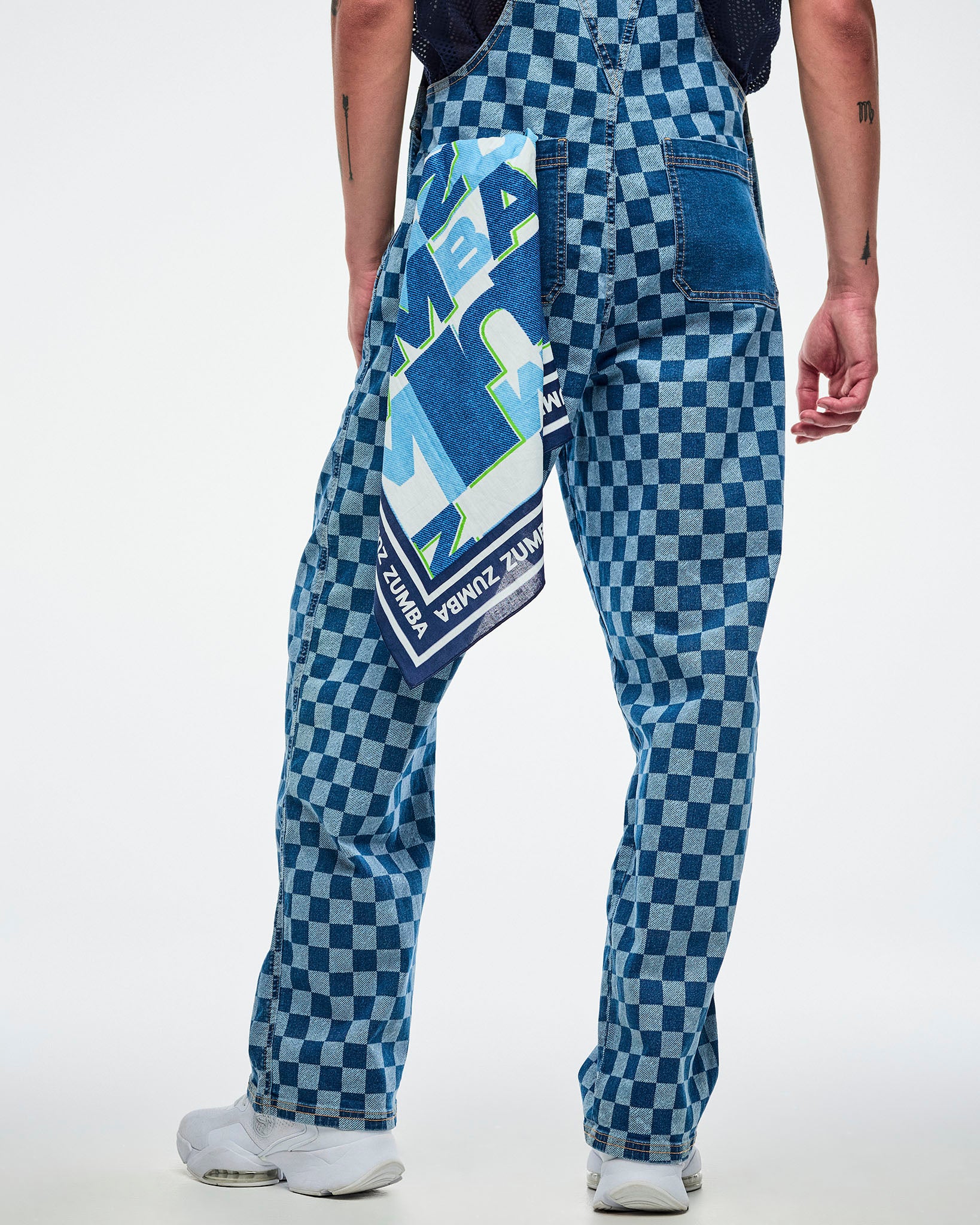 Male model in blue checkered overalls with a colorful patterned bandana hanging out of the back-left pocket.
