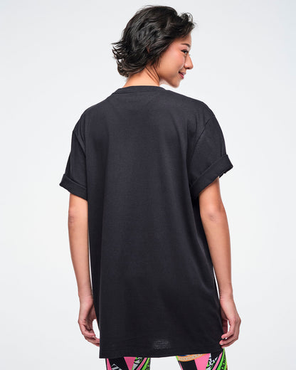 Back view of a female model wearing a black Zumba t-shirt on a white background.