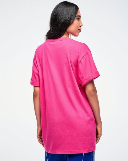 Back view of a female model wearing a pink Zumba shirt with colorful text on a white background.