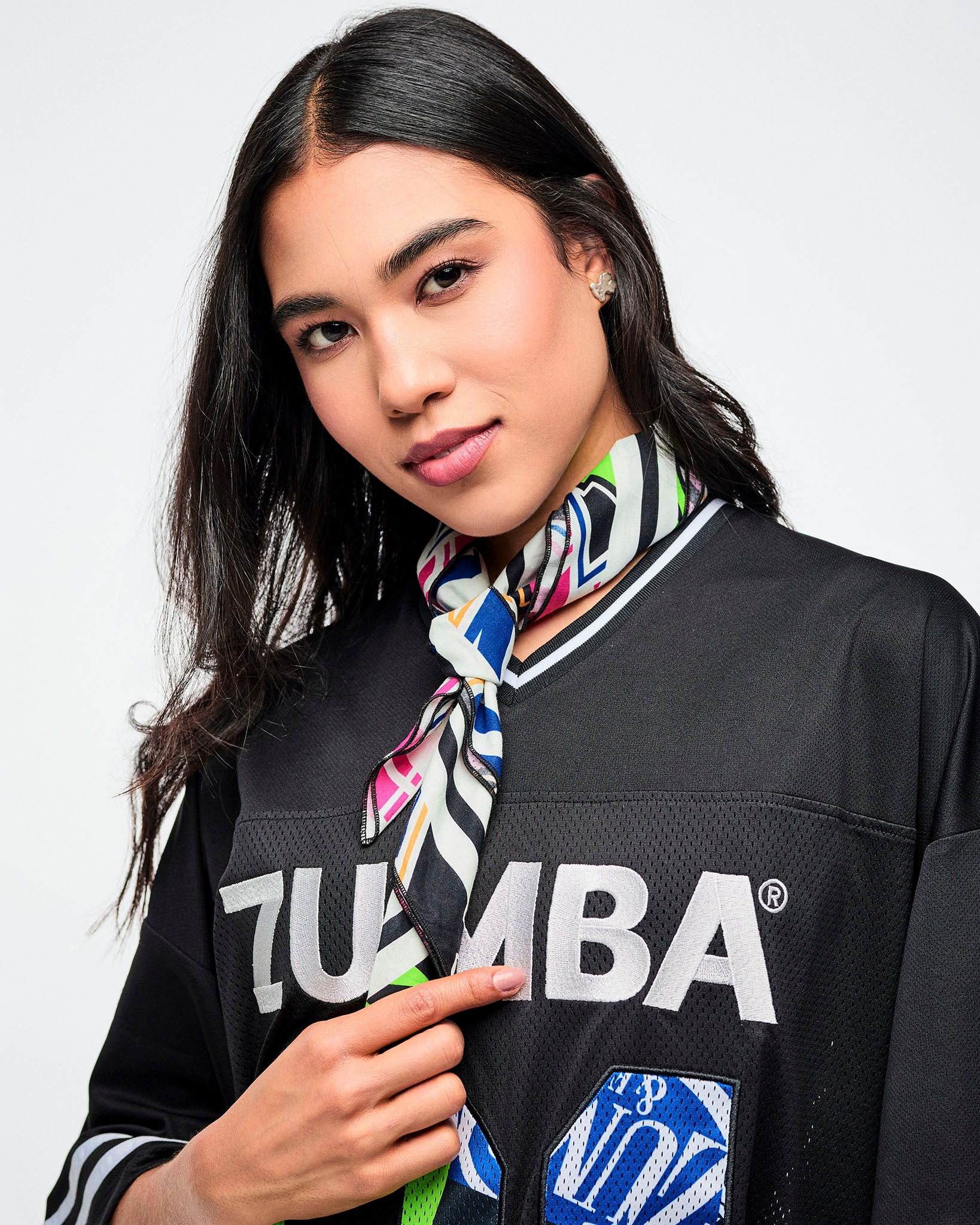 Female model wearing a black Zumba top with a colorful bandana tied around her neck on a white background.