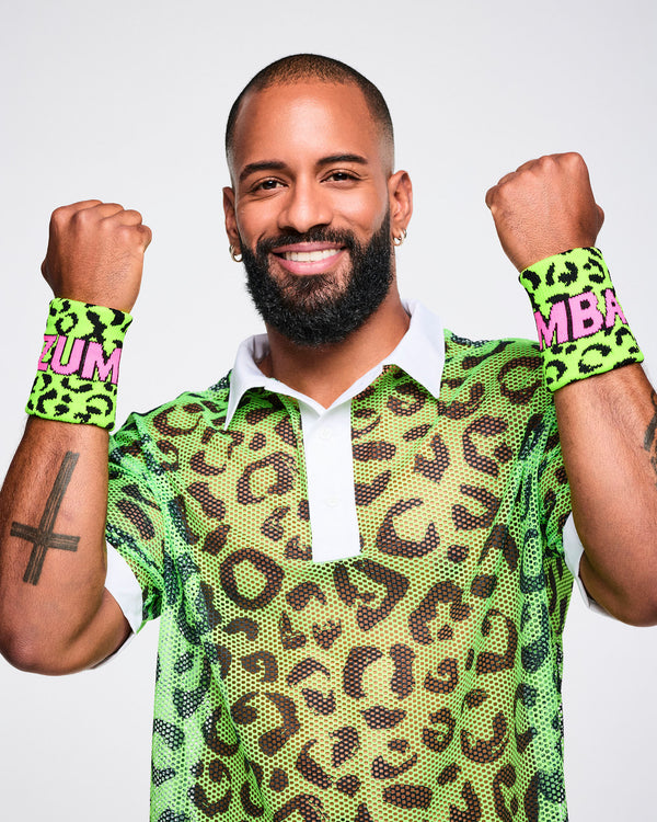 Male model wearing a green leopard print wristbands with ZUMBA in pink text, paired with a matching polo shirt. 