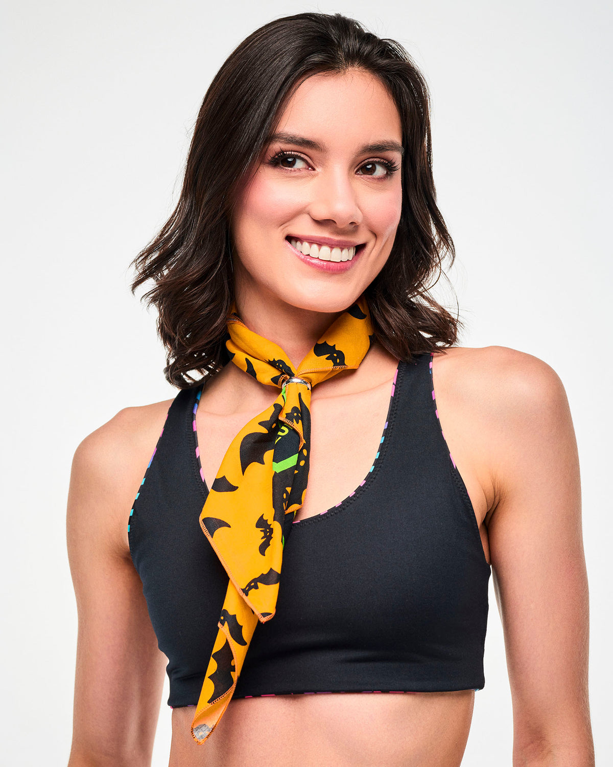 Close-up of a female model wearing an orange bat-print bandana tied around the neck over a black reversible bra top.