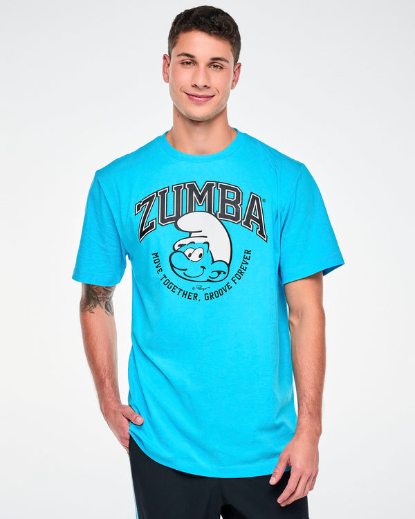 Male model in a blue crew neck tee with arched black varsity 'ZUMBA' text over a large smiling Smurf face in a white hat, framed by curved 'MOVE TOGETHER, GROOVE FOREVER' text. Paired with black pants.