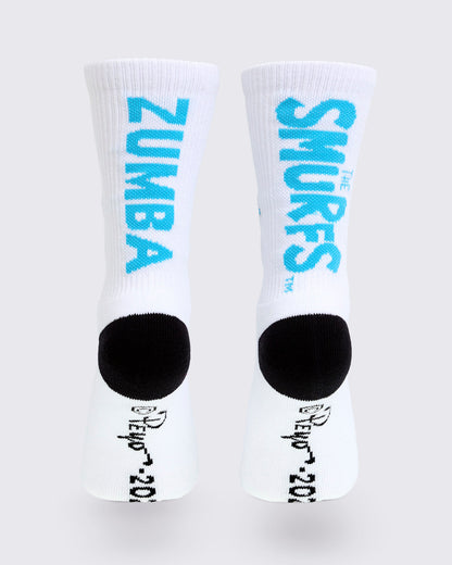Back view of the socks, with vertical blue 'ZUMBA' text on one sock and 'THE SMURFS' logo on the other above the black heels, plus a black '© Peyo 2026' signature along each sole.