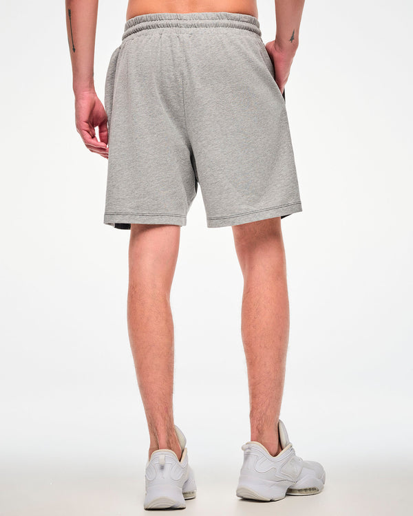 Shown from the back, male model wearing grey shorts paired with white sneakers.