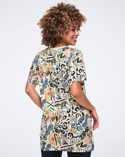Back view of a cream short-sleeve graphic T-shirt with a crew neckline, oversized fit, and allover multicolor abstract print. Female model wears the T-shirt over black leggings.
