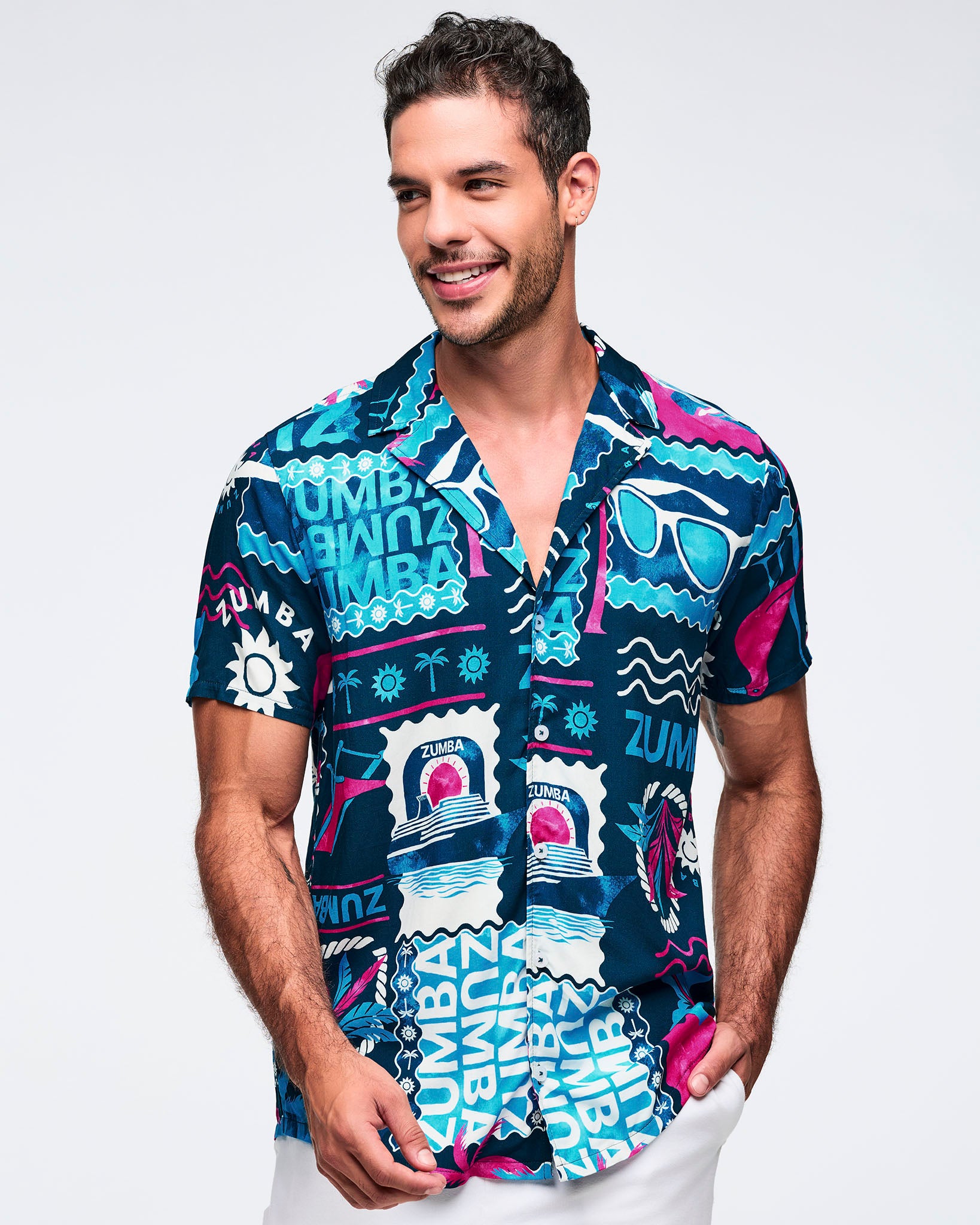 Navy short-sleeve button-up shirt with a relaxed collar and bold teal, white, and hot pink Zumba tropical graphic print throughout; shown on a male model with white shorts.