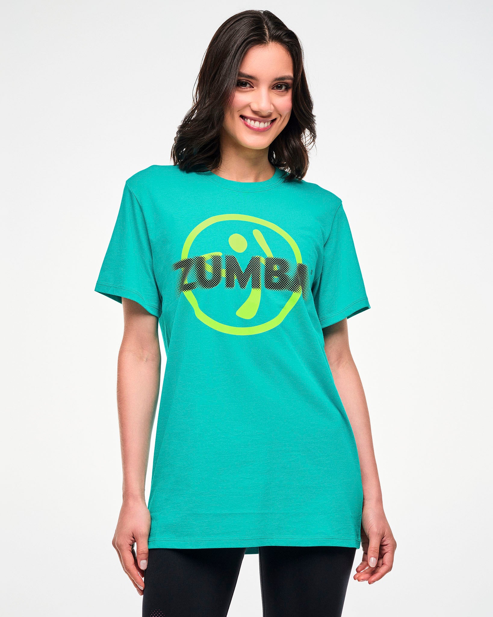 Female model wearing an aqua tee with a yellow Zumbito logo and halftone black dot "ZUMBA" text.