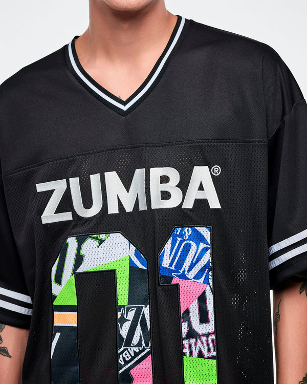 Close-up of a male model wearing a black Zumba jersey with silver “ZUMBA” text and a large colorful patterned “01.