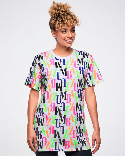 Female model wearing a colorful 'ZUMBA' patterned t-shirt against a white background.