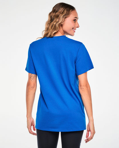 Shown from the back, a female model in the blue Smurfs graphic tee, showing the plain back and easy, relaxed fit through the body.