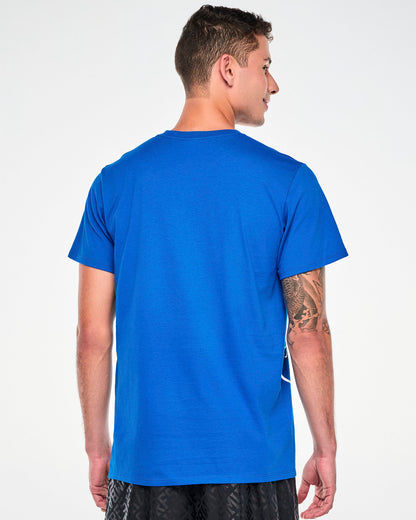 Back view of a male model in the blue Smurfs graphic tee, showing a plain back with a hint of the white Smurfs outline wrapping around the side, paired with black pants.